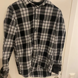 Svartvit flannel skjorta från Calvin Klein Jeans - Snygg svartvit rutig skjorta från Calvin Klein Jeans. Skjortan har långa ärmar och knappar framtill. Perfekt för en stilren look.