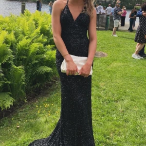 Svart glittrig långklänning - Säljer min fina balklänning som är svart och glittrig med öppen rygg samt har lite släp. Använd endast en gång så den är i mycket bra skick! Den är i strl 34 men skulle säga att den är ganska stretchig😁💕nypris är 4990 men säljer den för 3500