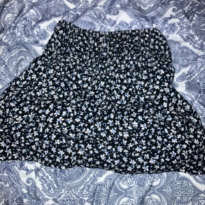 Blommig kjol från Zara - Säljer en söt blommig kjol från Zara i svart med små vita och blå blommor. Kjolen har en elastisk midja för en bekväm passform. Perfekt för en somrig look!💕💕