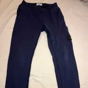 Mörkblå Stone Island Junior byxor - Snygga mörkblå byxor från Stone Island Junior med en praktisk ficka på sidan och det ikoniska märket på benet. Skicket på byxorna är 6,5/10. Äkta och Original!