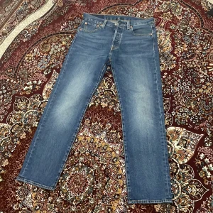 Blå jeansbyxor från Levi's - Snygga blå jeansbyxor från Levi's med klassisk femficksdesign och knappgylf. Perfekta för en avslappnad stil. Levi's-logga på bakfickan ger en ikonisk touch. Oanvända, endast testade storlek 30/30