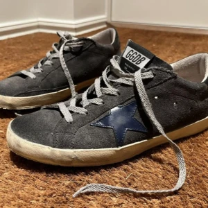  Golden Goose skor - Säljer nu mina sälltsynta ggdb skor, som är i en grå mocka med blå stjärna. Skick 8,5-10. Nypris runt 5500 kr, mitt pris 1800. Säljer dem eftersom de blivit för små. Strl: 40. Hör av dig vid minsta fundering 