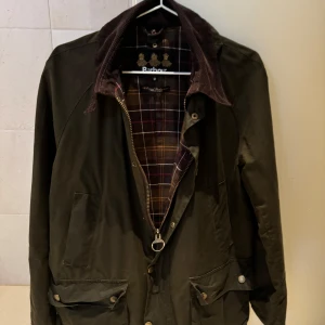 Barbour, oljerock/jacka -  klassisk olivgrön jacka från Barbour med brunt manchestertyg på kragen. Bra skick. Dm för mer bilder om det önskas. Nypris: 4100kr