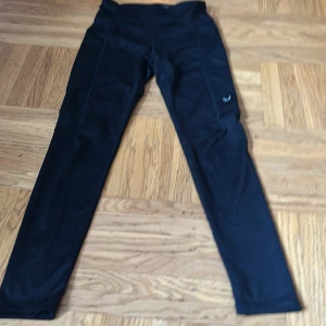 Svarta leggings från SOC i storlek 146/152💕💕💕 - Säljer ett par svarta leggings från SOC💕. De har en tight passform och är perfekta för träning💕Byxorna har reflexdetaljer på baksidan av benen för ökad synlighet💕Materialet är syntetiskt och stretchigt för bästa komfort💕💕Säljer dom för 50 kr💕💕Hör av er vid intresse av träningsbyxorna från SOC💕💕