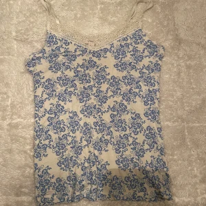 Blommig linne  - Säljer ett söt linne. Toppen har spetsdetaljer. Jag köpte tröjan i Spanien 
