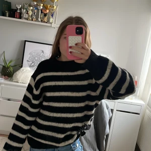 Svart och vit randig stickad tröja - Säljer en mysig svart och vit randig stickad tröja med långa ärmar. Perfekt för kyligare dagar och ger en avslappnad stil. Passar bra till jeans eller kjol.