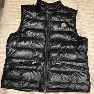 Moncler gui vest  - Jättebra skick, ÄKTA! Kvitto, galge, och allt som medföljer till västen följer även med vi köp av den. Storleken på västen motsvarar storlek S/M! Size 4! Ny kostar 9300kr, dock är denna storlek eftertraktad.