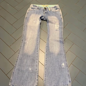 Blå bootcut jeans  - ( BILDER FRÅN FÖRRA SÄLJAREN ‼️De passade inte mig så har inte använt dom så dom är i samma skick som på bilden ❗️) Snygga ljusblå bootcut jeans med slitna detaljer och en cool tvätt. De har en låg midja och klassisk femficksdesign. Midjemåttet tvärs över är 39cm och innerbenslängden är 82cm! 