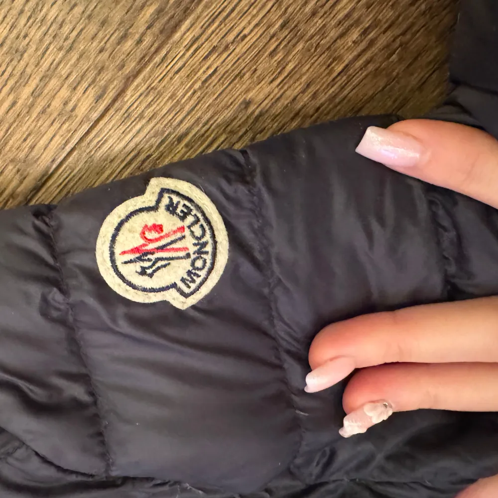 Säljer en stilren svart dunjacka från Moncler. Jackan har en hög krage och dragkedja framtill. Den är quiltad med två framfickor och Moncler-loggan på ärmen.storlek 2. Takit.