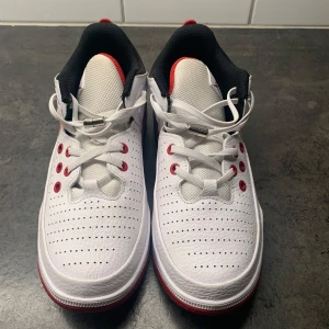 Vita och röda sneakers från Jordan - Snygga vita sneakers med röda och svarta detaljer från Jordan. Skorna har snörning och perforerade detaljer. De är i storlek 36 och är helt oanvända. 