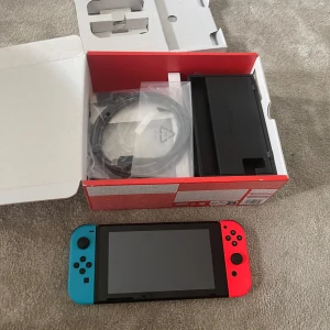 Nintendo Switch med neonröda och neonblå Joy-Con - Säljer en Nintendo Switch med neonröda och neonblå Joy-Con. Konsolen kommer i originalförpackning med alla tillbehör som HDMI-kabel och dockningsstation. Perfekt för spelkvällar och gaming på språng! 🎮
