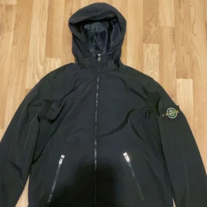 Svart jacka från Stone Island - Säljer en svart jacka från Stone Island med huva och dragkedja. Jackan har två fickor med dragkedjor.