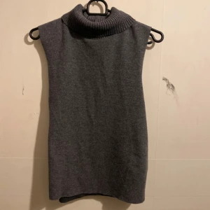 Grå ärmlös polotröja - Snygg grå ärmlös polotröja med ribbad krage. Perfekt för lager-på-lager eller som den är. Passar både till vardags och mer uppklädda tillfällen.