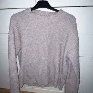 Beige stickad tröja från H&M - Mysig beige stickad tröja från H&M med ribbad struktur. Perfekt för kyliga dagar med sin klassiska design och långa ärmar. Ett måste i garderoben för en stilren look.