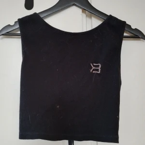 Svart ribbad linnetopp better bodies - Snygg svart ribbad linnetopp med en liten logga på bröstet. Perfekt för en stilren och enkel look. Passar bra till både jeans och kjol. Även träning