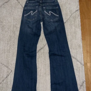 Blå bootcut low waisted jeans - Snygga blå bootcut jeans som är low waisted ifrån Nelly i storlek 34.