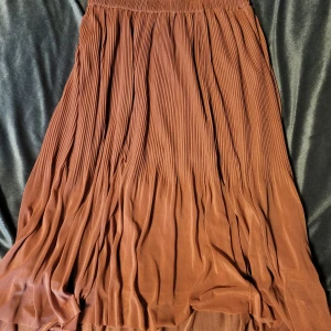 Rosa plisserad kjol från Reserved - Säljer en elegant rosa plisserad kjol från Reserved. Kjolen har en mjuk och flödande design med elastisk midja för extra komfort. Perfekt för att ge en stilfull touch till din outfit.