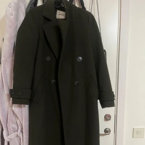 Svart kappa från & other stories - Elegant mörk grön kappa från & other stories i 100% wool. Dubbelknäppt design med långa ärmar och klassisk krage. Perfekt för kyligare dagar. Storlek är XS