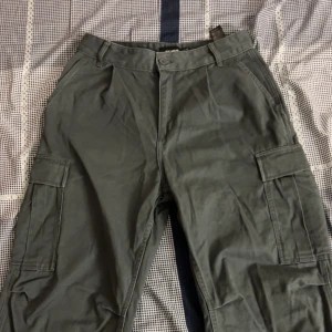 Gröna/Gråa cargobyxor från Pull&Bear - Snygga gröna cargobyxor från Pull&Bear med praktiska fickor på sidorna. Perfekta för en avslappnad stil. Tillverkade i ett slitstarkt material.