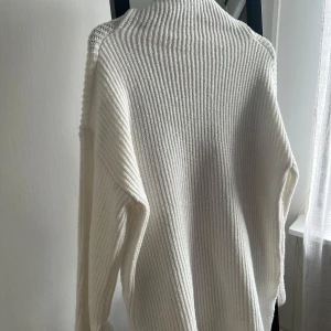 Stickad tröja  - En mysig och lång tröja med hög krage.