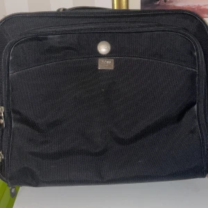 Svart datorväska från Boss - Snygg och praktisk svart datorväska från Boss med Dell-märke. Väskan har flera fack och dragkedjor för enkel organisering. Perfekt för att bära din laptop och andra viktiga tillbehör.