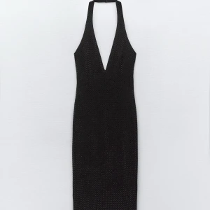 Svart glittrig klänning - Elegant svart klänning med djup v-ringning och halterneck-design. Klänningen är glittrig och har en slits baktill för extra stil. Oanvänd med prislappar på! 
