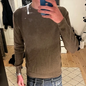 Stickad tröja - Säljer denna stickade tröja i en beige/brun färg från märket lagency. Tröjan är i topp skick men har tyvärr blivit för liten för mig. Köpt på thernlunds för 1200. 