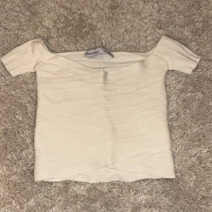 Vit offshoulder topp från Bershka - Snygg vit offshoulder topp från Bershka. Den är ribbad och har en tight passform som framhäver figuren. Perfekt för en stilren look. Sällan använd.