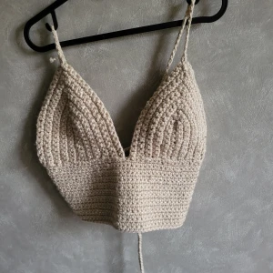 Beige virkad linne-topp - Säljer en handgjord beige virkad linne-topp med smala axelband och snörning i ryggen. Perfekt för sommardagar och festivaler. Toppen har en unik och bohemisk stil. Ingen storlek då den är handgjord, uppskattas till s/m. 