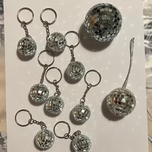 Nyckelringar och dekorationer med discokulor - Säljer ett set med glittriga discokulor i form av nyckelringar och dekorationer. Perfekt för att ge en festlig touch till dina nycklar eller som dekoration. Kulorna är täckta med små spegelbitar som reflekterar ljus.