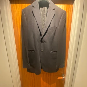 Nattblå/mörkblå kavaj från Tiger of Sweden - Elegant nattblå kavaj från Tiger of Sweden i 100% ull. Kavajen har två knappar framtill och klassiska fickor. Perfekt för en stilren look. Inköpt för ca 3499kr. Ganska bra skick därav priset. Bara att skriva pm för frågor eller fler bilder.