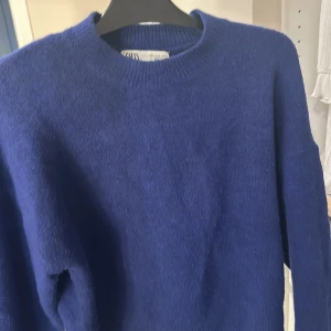 Blå tröja från Zara - Säljer en stilren blå tröja från Zara. Den har en klassisk rund hals och långa ärmar, perfekt för kyligare dagar. Tröjan är mjuk och bekväm, vilket gör den till ett utmärkt val för både vardag och avslappnade tillfällen.