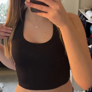 Svart ribbad linnetopp - Säljer en svart ribbad linnetopp med rund halsringning. Toppen är ärmlös och har en tight passform, perfekt för sommardagar.