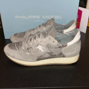 Grå sneakers från Philippe Model - Säljer ett par feta gråa Philippe model med camouflage mönster, är i riktigt bra skick , smått använda, men inga större slitage. Påse och box medföljer. Skriv gärna om ni har frågor eller eventuella prisförslag🤗