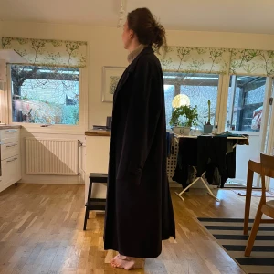 Marinblå lång kappa - Elegant svart lång kappa med klassisk design. Perfekt för kyligare dagar med sin stilrena look och långa ärmar. Passar bra över både vardags- och festkläder.