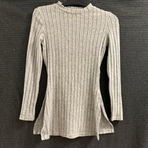 Grå ribbad stickad tröja - Snygg grå ribbad stickad tröja med långa ärmar och slitsar på sidorna. Är en pärfäkt hemma tröja och ute tröja. Den formar sig perfekt efter din kropps form 