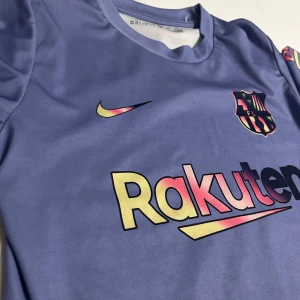 Lila barcelona tröja - Snygg lila barcelona från Nike med korta ärmar och barca på bröstet. Tröjan har Dri-FIT-teknologi för att hålla dig sval och bekväm. Perfekt för barca fans