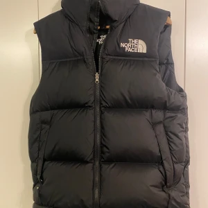 Svart dunväst från The North Face - Säljer en svart dunväst från The North Face i storlek S. Den är i mycket fint skick!