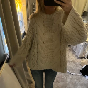 Vit stickad tröja - Mysig vit/ljusbeige stickad tröja med kabelstickat mönster. Tröjan har en avslappnad passform och långa ärmar, perfekt för kyliga dagar. Väldigt skön i materialet och varm❤️