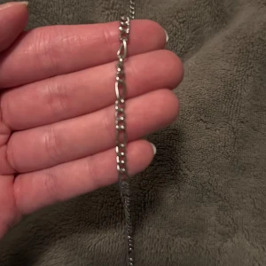 Silverfärgad fotlänck - Elegant silverfärgad fotlänk med en tunn kedja och små detaljer. Perfekt för att ge en subtil glans till din outfit.