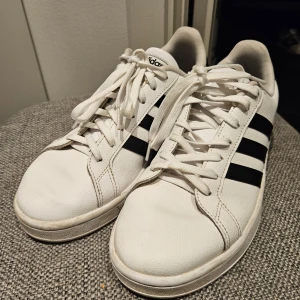 Vita Adidas sneakers - Säljer ett par klassiska vita Adidas sneakers i mycket bra skick. Perfekta för vardagsbruk och passar till det mesta i garderoben. Strl 41  1/3. Hör av er vid funderingar eller fler bilder