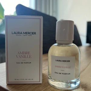 Laura Mercier Ambre Vanille Eau de Parfum - Säljer en  parfym från Laura Mercier, Ambre Vanille. Flaskan är stilren och genomskinlig med en enkel vit etikett och ett matchande vitt lock. Doften är en härlig blandning av ambra och vanilj, perfekt för både dag och kväll. Endast test sprayad. 