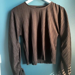 Brun Topp XS - Snygg brun topp med långa ärmar och band i ärmslutet.