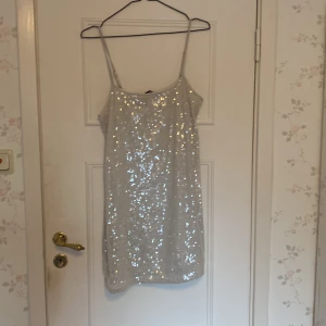 Glittrig klänning från H&M Divided - Säljer en snygg glittrig klänning från H&M Divided. Klänningen är kort längd, perfekt för en festlig kväll. Den är täckt med paljetter som ger en glittrande effekt. Passar perfekt för att sticka ut på festen! ✨