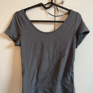 Grå kortärmad topp - Säljer en enkel och stilren grå topp med korta ärmar och rund halsringning. Perfekt för en avslappnad look.