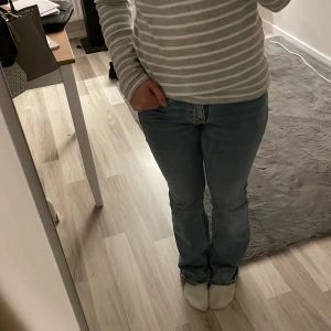 LjusBlåa bootcut jeans - Säljer ett par klassiska blå bootcut jeans med en snygg passform. De har en normal midja och är perfekta för en avslappnad stil. Jeansen har en dragkedja och knapp framtill.