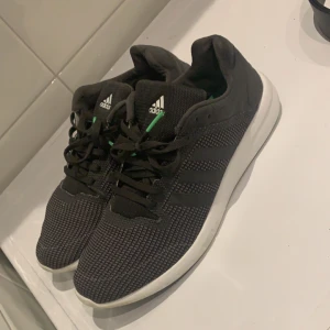 Svarta sneakers från Adidas - Snygga mörkgröna sneakers från Adidas med vit sula och klassiska tre ränder på sidan. Skorna har snörning och en diskret grön detalj på insidan av hälen. Perfekta för en casual look, funkar även minst lika bra för en joggingtur etc./// Har endast andvänt skorna 2  gånger eftersom jag har andra löparskor och nu ligger de bara där och tänkte att de kan komma till användning av någon annan. Ny pris ligger på ca 800-1000kr beroende på hemsida men säljer de naturligtvis för ett optimalt pris här.