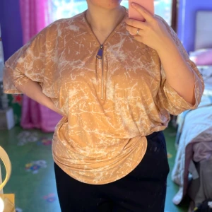 Beige mönstrad blus från QED London - Säljer en beige blus från QED London med ett unikt mönster i vitt. Blusen har en lös passform och trekvartsärmar. Den har en dragkedja framtill som en snygg detalj. Perfekt för en avslappnad stil. Storlek M/L 