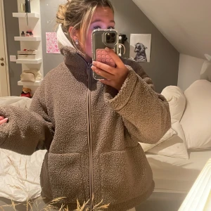 Brun teddyjacka med dragkedja - Mysig brun teddyjacka med dragkedja framtill. Jackan har en perfekt passform och långa ärmar, perfekt för kyliga dagar. Storlek lx men därför perfekt att ha över stickade eller hoodies, sitter som m. Jag är 159 cm❤️lapp är kvar