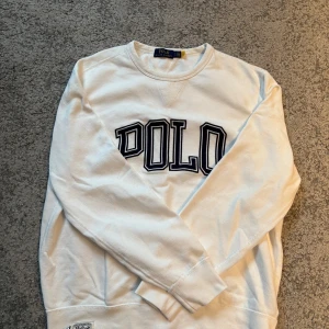 Vit sweatshirt från Polo Ralph Lauren - Säljer en stilren vit sweatshirt från Polo Ralph Lauren med svart text på framsidan. Storlek L men sitter även bra för storlek M. Hör av dig om du är intresserad!
